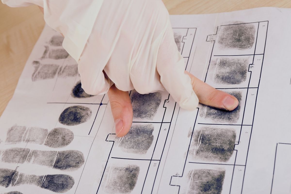 Hand with white glove taking fingerprints.